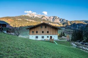 a barn on a hill with mountains in the background at Mittnackerhof Apartment Melisse in Sarntal