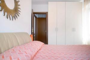a bedroom with a pink bed and white cabinets at La Piazzetta in Germignaga