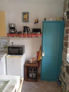 Eine Küche mit einer blauen Tür neben einem Kühlschrank in der Unterkunft Tiny Cantalou in Saint-Martin-sous-Vigouroux