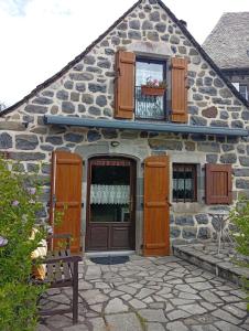ein Steinhaus mit Holztür und Fenstern in der Unterkunft Tiny Cantalou in Saint-Martin-sous-Vigouroux