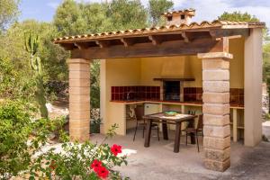 an outdoor kitchen with a pergola and a table at Sa Carbona in Artá