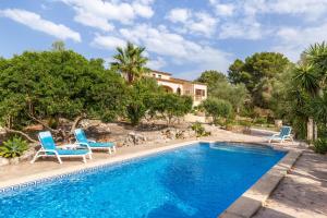 a swimming pool with two blue chairs and a house at Sa Carbona in Artá