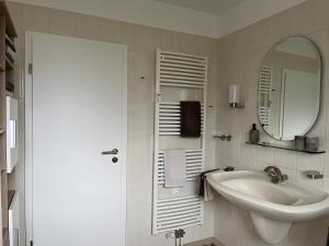 a white bathroom with a sink and a mirror at Haus Blumenglück in Herscheid
