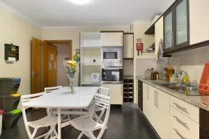 a kitchen with a white table and chairs in it at Apartamento Jade in Caniço +7 photos
