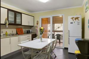 a kitchen with a table and chairs and a refrigerator at Apartamento Jade in Caniço