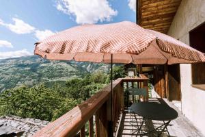 a patio with a chair and an umbrella on a balcony at Chalet cosy in Bourg-Saint-Maurice