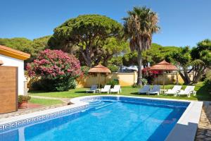 a swimming pool in a yard with chairs and trees at Magnolia A - Solo Familias in Conil de la Frontera