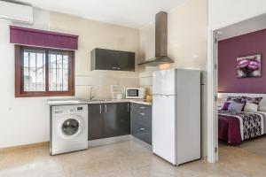 a kitchen with a washing machine and a bed at Magnolia A - Solo Familias in Conil de la Frontera