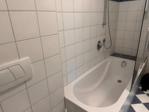a white bath tub in a white tiled bathroom at Atelierwohnung Bei München in Pfaffenhofen an der Ilm