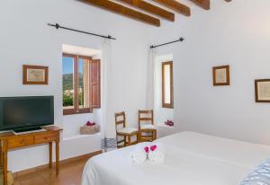 a white bedroom with a bed and a tv at Historic Finca in Mallorca Up To 8 in Andratx