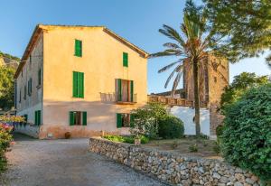 a building with a palm tree and a stone wall at Historic Finca in Mallorca Up To 8 in Andratx
