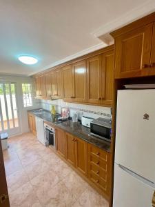 a kitchen with wooden cabinets and a white refrigerator at Relax Inn in Pilar de la Horadada