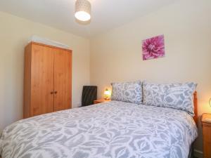 a bedroom with a bed and a wooden cabinet at The Turbles - Swallows Nest in Castlemorton