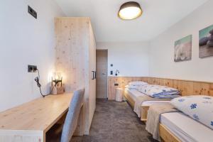 a room with two beds and a wooden table at Living Lerchna -Apartment Morgentau in Maranza