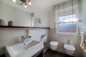 a bathroom with a sink and a toilet and a mirror at Schnitzer Ferienwohnung Enzian in Rablà +15 photos