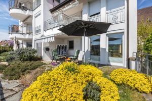 a patio with an umbrella and yellow flowers in front of a building at Ferienwohnung Rheinblick in Küssaberg
