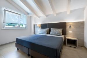 a bedroom with a bed with a blue bedspread and a window at Eco del Garda Apartments in Tenno +56 photos