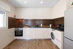 a kitchen with white cabinets and a washer and dryer at Pontes Guest House in Arcozelo