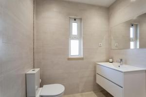 a white bathroom with a toilet and a sink at Villa Isabel in Vale do Lobo