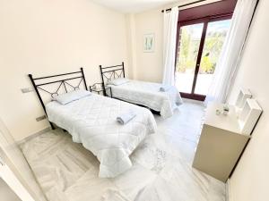 a white bedroom with two beds and a window at Villa with Private Pool in Estepona +16 photos