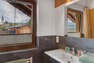 a bathroom with a sink and two windows at Ferienwohnung Haus Brugger in Uttendorf