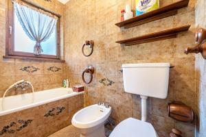 a bathroom with a toilet and a tub and a sink at Ciasa Apelli in Pozza di Fassa
