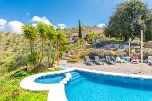 a swimming pool in a yard with chairs and trees at Finca Las Nuevas Casa Carmen in Alora