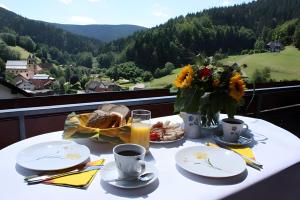 a table with a breakfast of bread and flowers on a balcony at Haus Margot Armbruster in Bad Rippoldsau-Schapbach