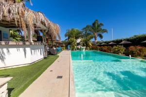 a swimming pool next to a resort with trees at Saija Apartment con piscina in Pozzallo +18 photos