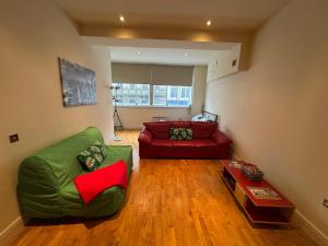 a living room with a green couch and a red chair at Cardiff City Escapes in Cardiff