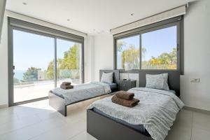 two beds in a bedroom with large windows at Villa Palacio Nazari in Málaga +36 photos