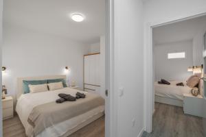 a white bedroom with two beds and a mirror at Casa Us in Arinaga