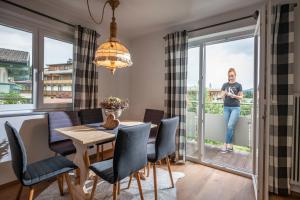 a woman standing on a balcony in a dining room with a table and chairs at Apartment Eve in Söll