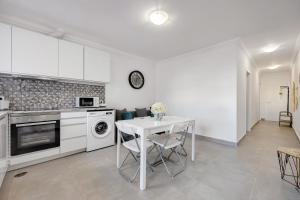 a kitchen with a white table and a white stove top oven at Yasmim House in Sagres