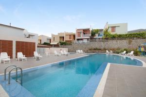 a swimming pool with white chairs and chairs next to a building at La Quinta Adosado in Santa Úrsula