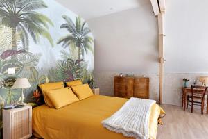 a bedroom with a yellow bed with a palm mural at Chambre Terracotta in Tavant