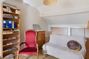a bedroom with a bed and a red chair at Chambre Terracotta in Tavant