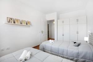 a white bedroom with two beds and white cabinets at Oramas Beach House – Pool & Terrace in Puertito de Güímar +20 photos