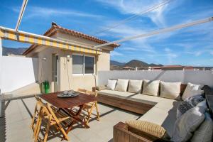 a patio with a couch and a table on a balcony at Oramas Beach House – Pool & Terrace in Puertito de Güímar