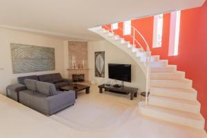 a living room with a staircase with a couch and a tv at Villa Maitreya in Son Bou