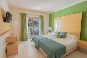 a bedroom with a large bed with green walls at Villa Maitreya in Son Bou +35 photos