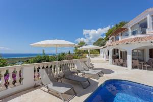 a house with a swimming pool and chairs and an umbrella at Villa Maitreya in Son Bou