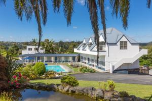 a house with a swimming pool and palm trees at Aloha Seaview Resort Motel in Paihia