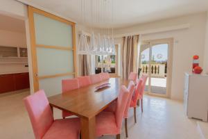 a dining room with a wooden table and pink chairs at Villa Maitreya in Son Bou