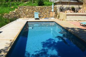 a swimming pool in a backyard with a wooden deck at La Rectoría de Castellar in La Vall de Bianya