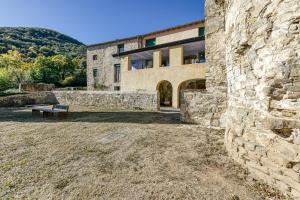 a stone building with a bench in front of it at La Rectoría de Castellar in La Vall de Bianya
