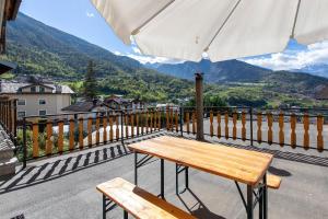 a wooden bench sitting on a balcony with an umbrella at Il Borgo - Aymavilles in Aymavilles