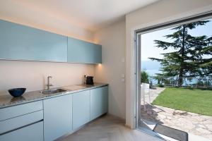 a kitchen with white cabinets and a large window at Villa Gargnano in Gargnano
