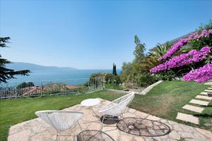 a patio with two chairs and a table and flowers at Villa Gargnano in Gargnano