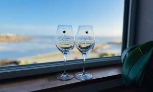 two wine glasses sitting on a window sill at Appartement duplex vue mer in Audierne